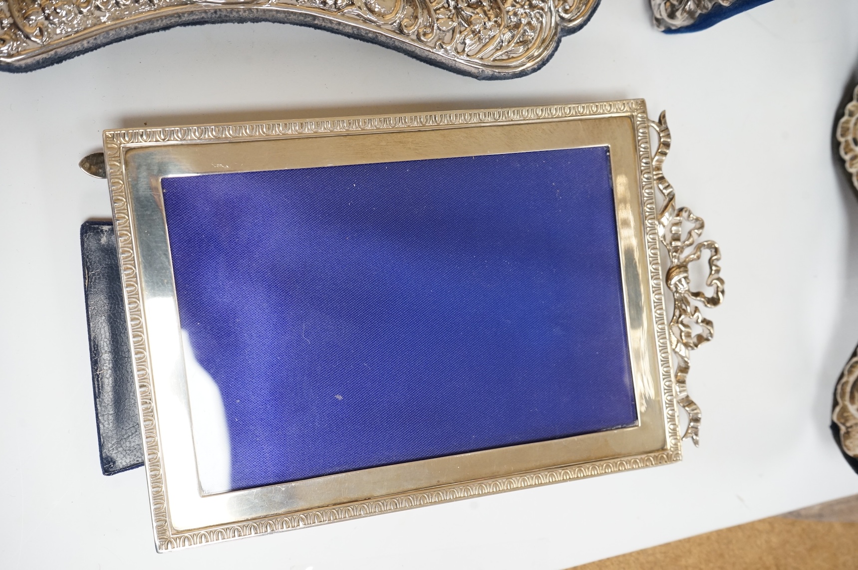 A George V silver mounted rectangular photograph frame, with ribbon bow crest, by Stokes & Ireland Ltd, Chester, 1912, 18.2cm including crest, together with ten other modern silver mounted photograph frames, largest 29.4